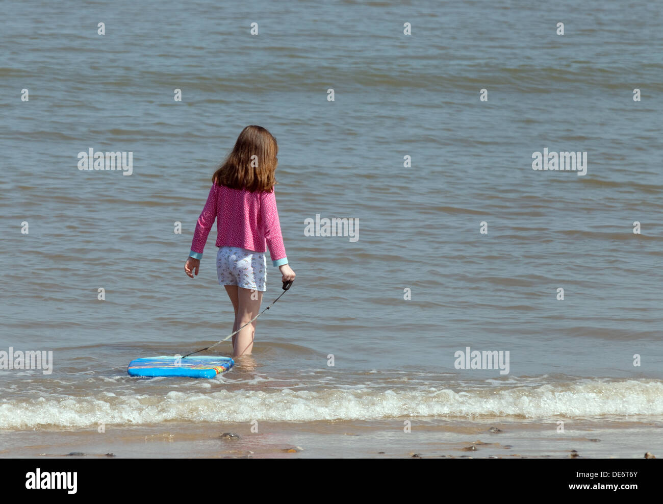 Young girl age 5-6 years paddling in the sea on the beach on summer holiday, Mundesley Beach, Norfolk, UK Stock Photo