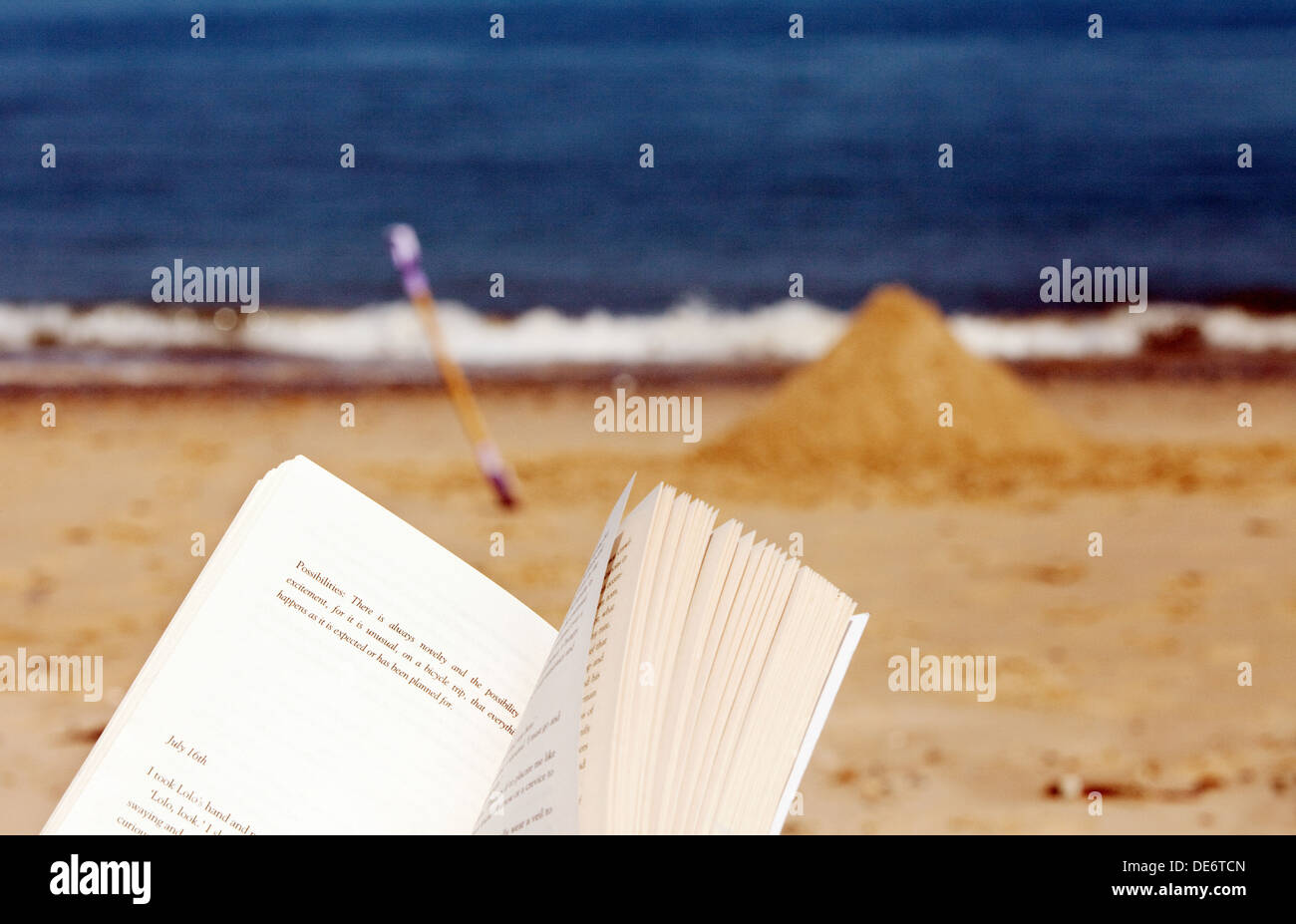 Reading a book on the beach on a summer holiday, Mundesley Beach, Norfolk East Anglia England UK Stock Photo