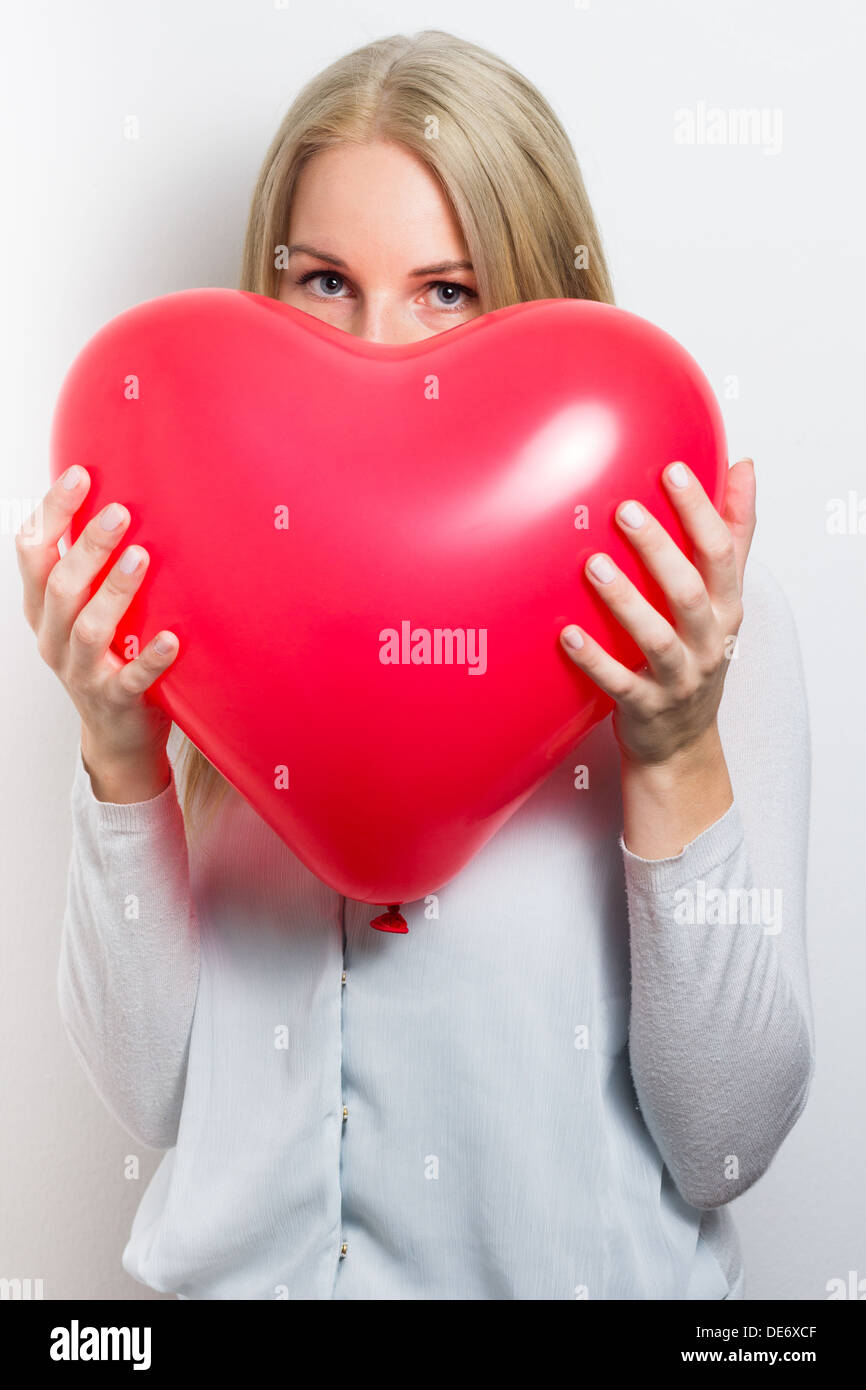 Blonde woman hiding her face behind a red heart for valentin´s day Stock Photo