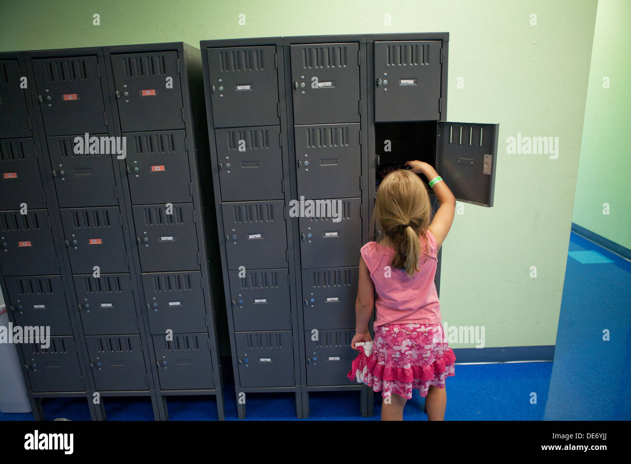 Eight year old girl opens her locker. Stock Photo