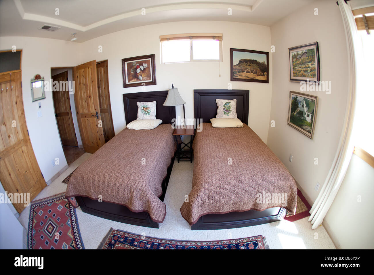 Bedroom with art hanging on the walls and two beds.  Southwestern USA home. Stock Photo