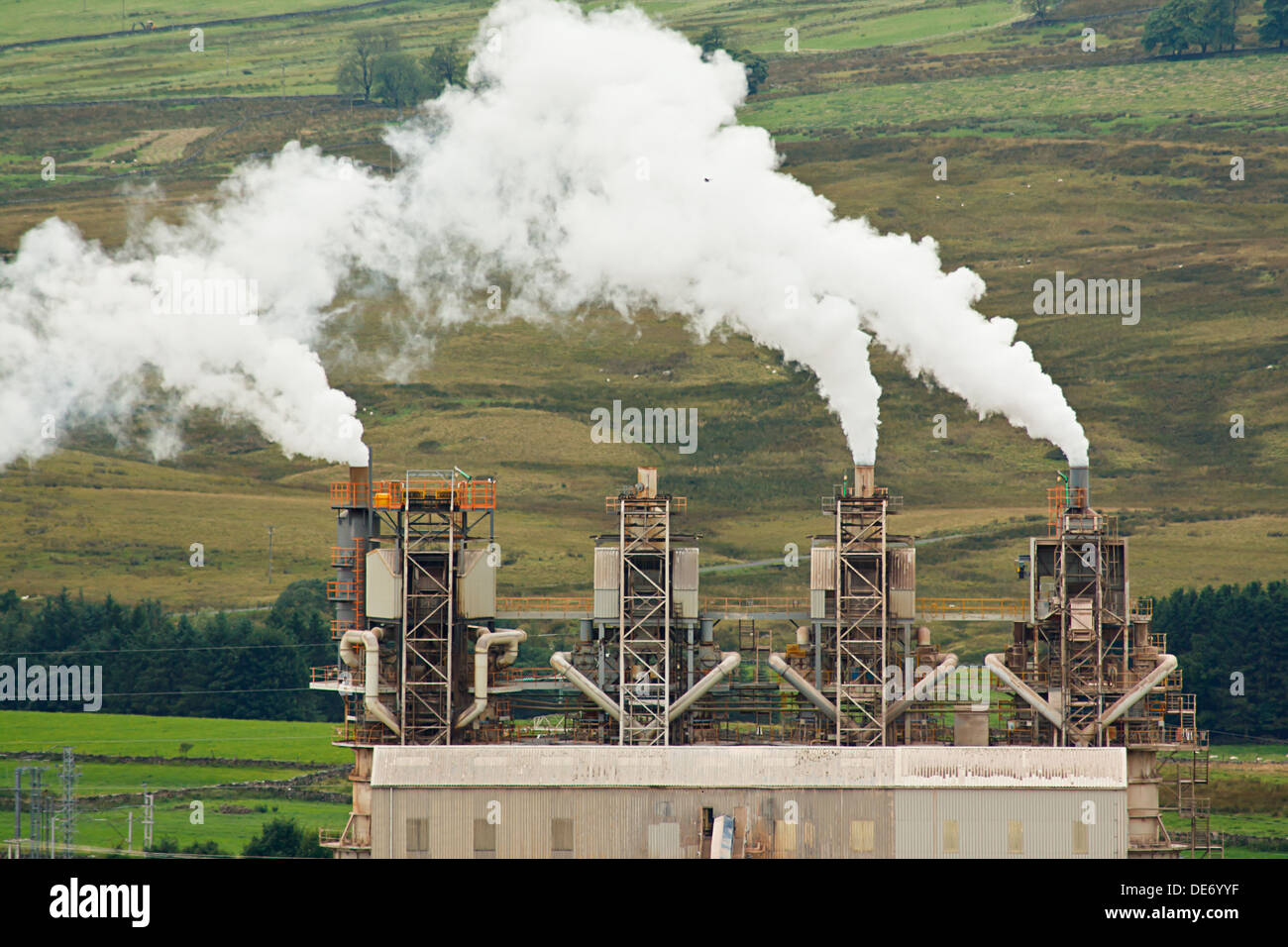 Four industrial chimneys emitting smoke into the environment Stock Photo