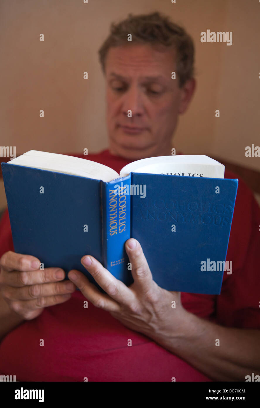 Middle aged man reading Alcoholics Anonymous text, also called the Big Book in recovery groups. Stock Photo