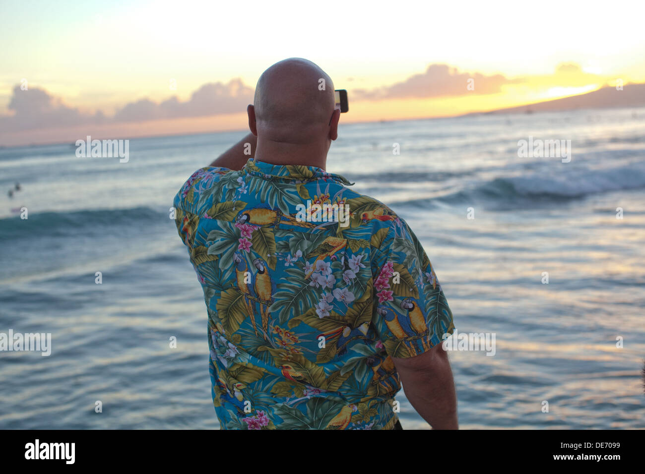 Tourist in Hawaii takes a picture of the ocean sunset with his phone. Stock Photo