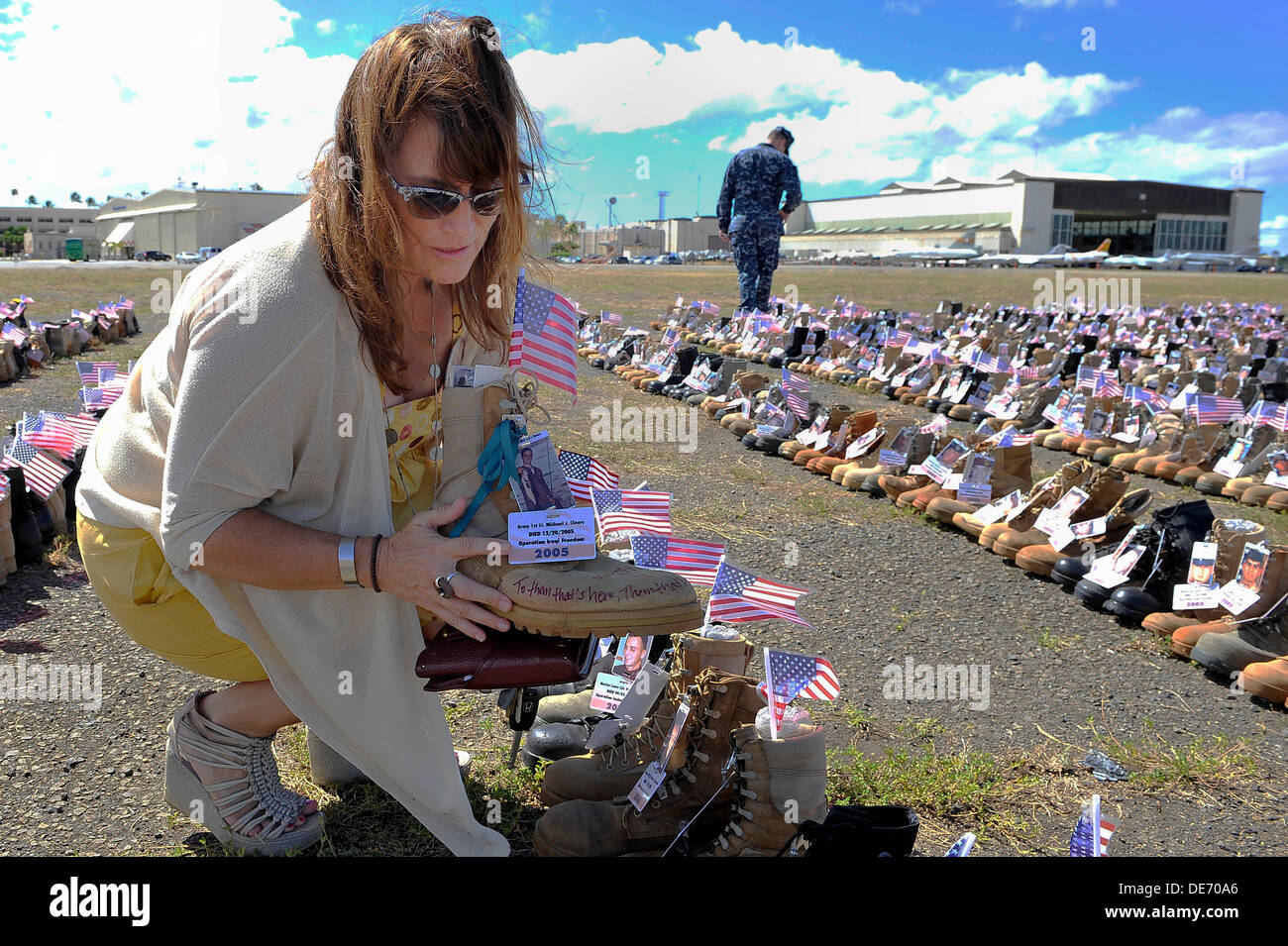 Shannon Cleary, sister of Army 1st Lt. Michael J. Cleary, who lost his life on during Operation Iraqi freedom displays her brother's boot during a memorial made from the 6,000 boots with the names and pictures of those killed in the Iraq and Afghan Wars on display on Ford Island Joint Base Pearl Harbor-Hickam September 11, 2013 in Pearl Harbor, Hawaii. Stock Photo