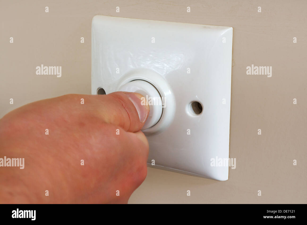 pressing an energy efficient timed light switch designed to save electricity and reduce power usage Stock Photo
