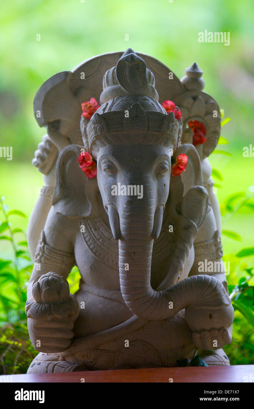 white stone statue of Hindu god Ganesha adorned with red flowers Stock Photo
