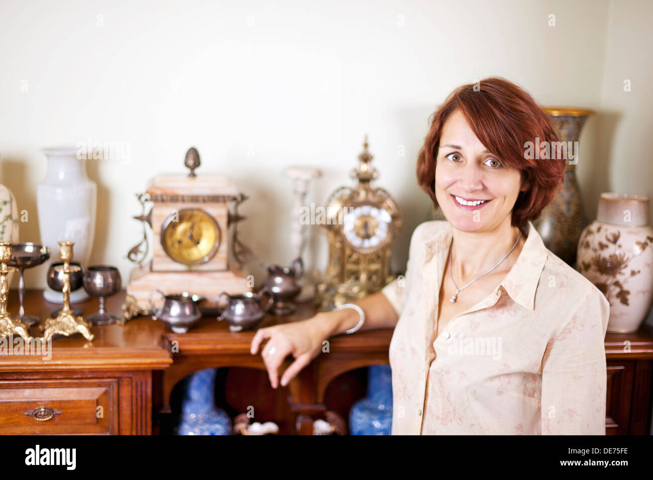 Happy proud woman standing next to her collection of antiques Stock Photo