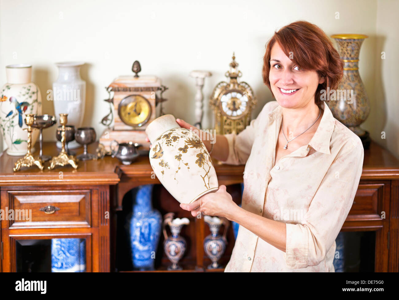 Proud woman holding vase from her collection of antiques Stock Photo