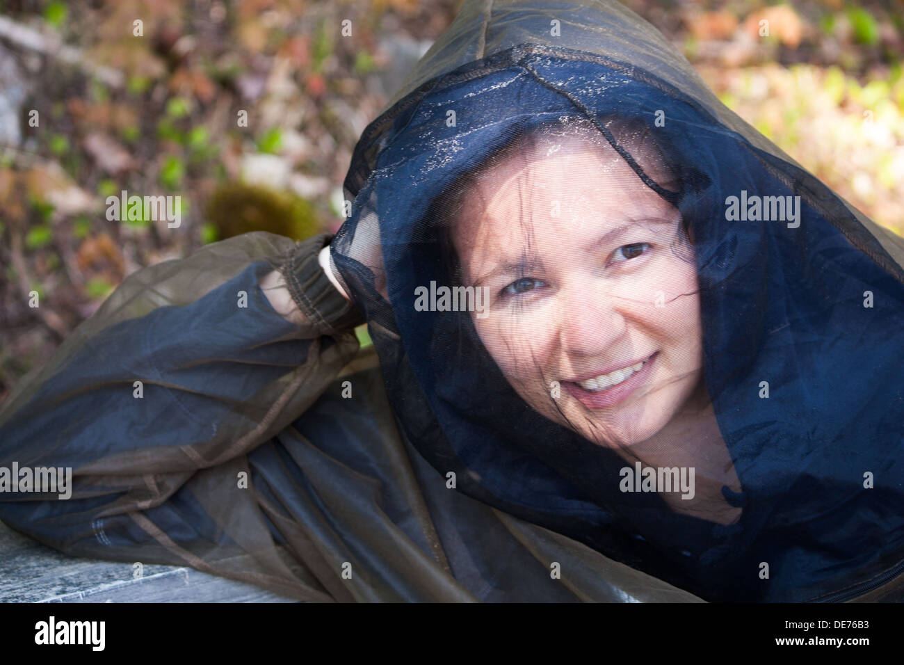 A Young woman camping in Northern Ontario in May wears bug protection gear to avoid mosquitoes that can carry West Nile Virus Stock Photo