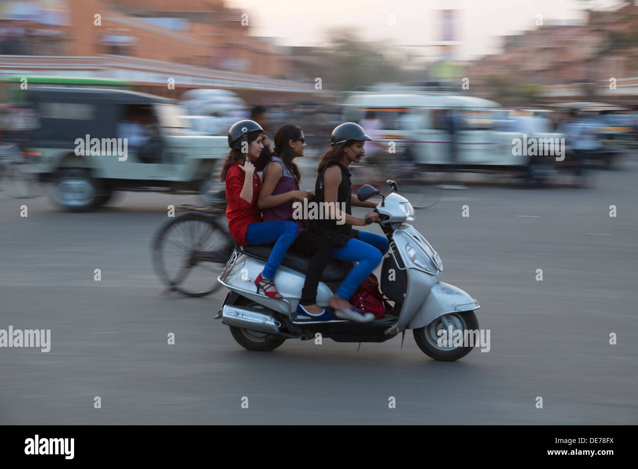 India, Rajasthan, Jaipur, three girls on a scooter in rush hour traffic. Motion blur effect. Stock Photo