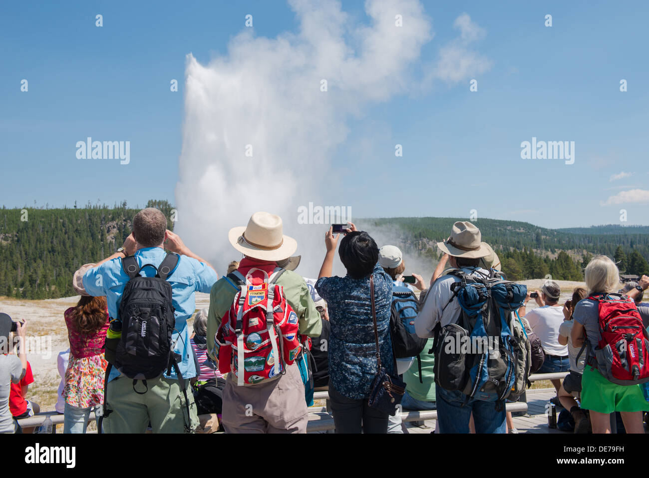 Photograph of a group of people enjoying an eruption of Yellowstone's Old Faithful Geyser. Stock Photo