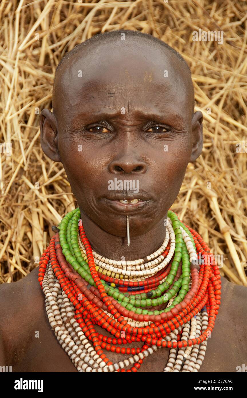 Karo woman with lots of colorful necklaces and Cowry shells, lip piercing  and facial paintings in front of her hut, Omo river Stock Photo - Alamy