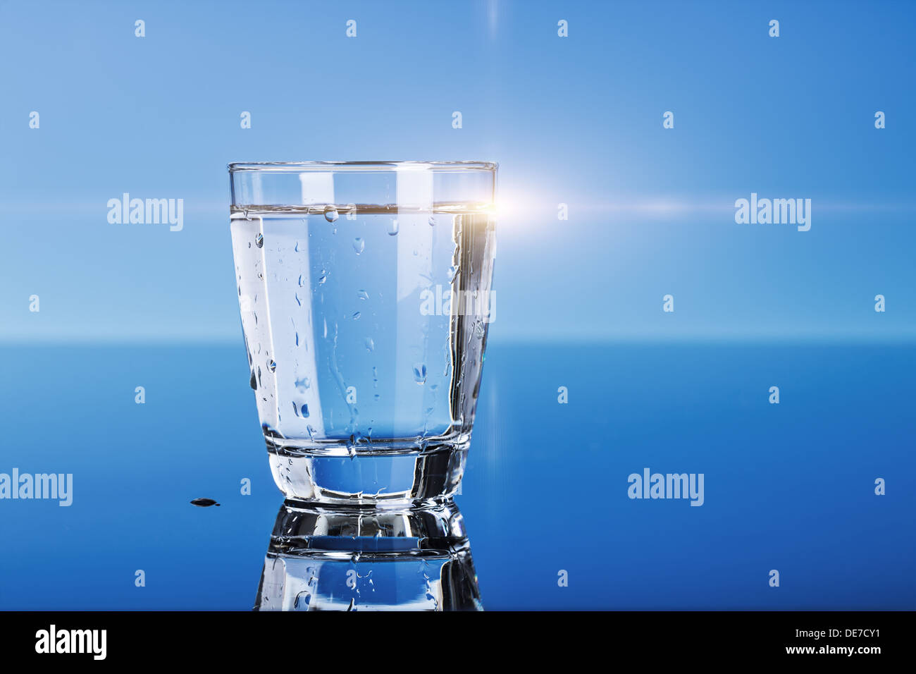 glass of drinking water on a blue table Stock Photo Alamy