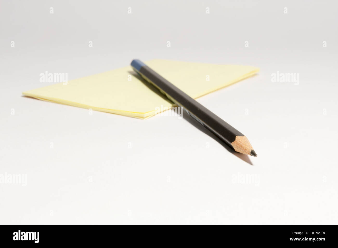 Pencil and blank post it note pad on white background Stock Photo