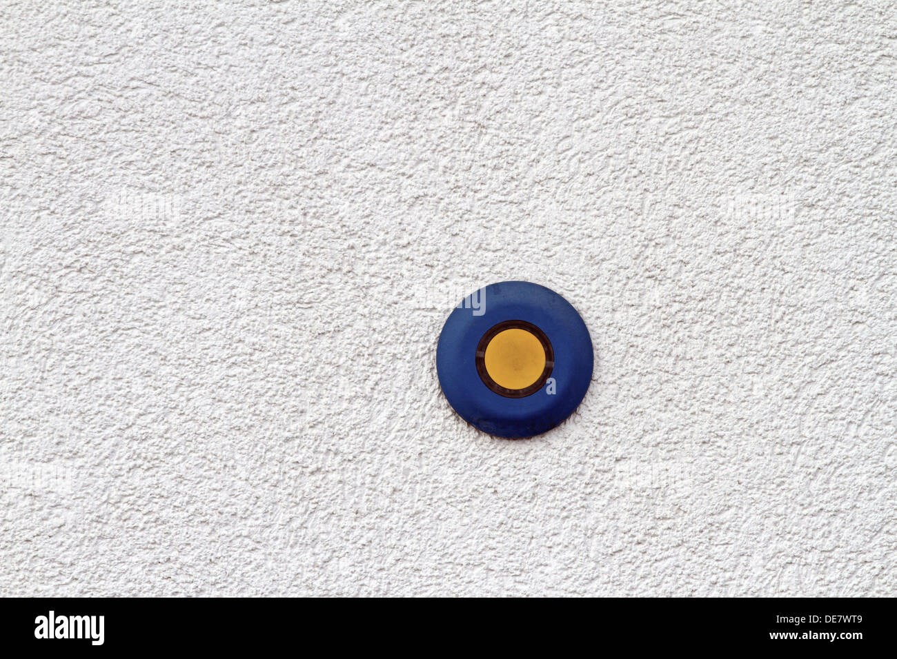 abstract view of blue and yellow button on mortar finished wall Stock Photo