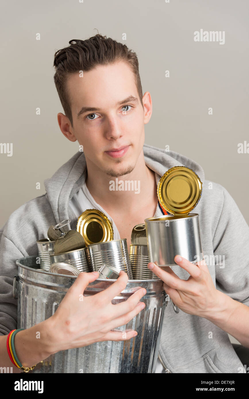 Eco friendly young man holding trash can, recycling metal tins Stock Photo
