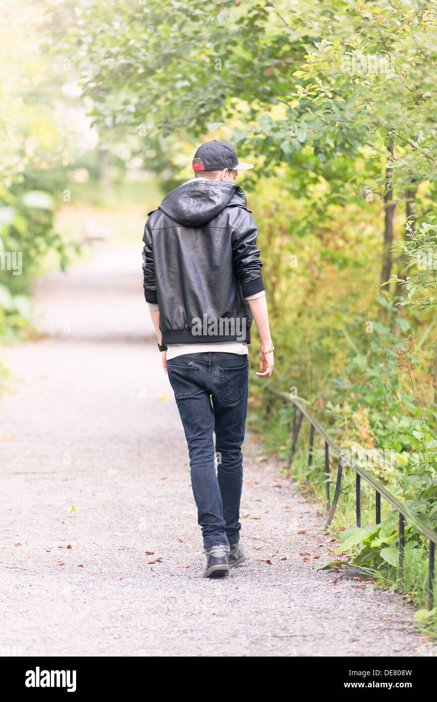 Young man walking away on footpath in a park Stock Photo