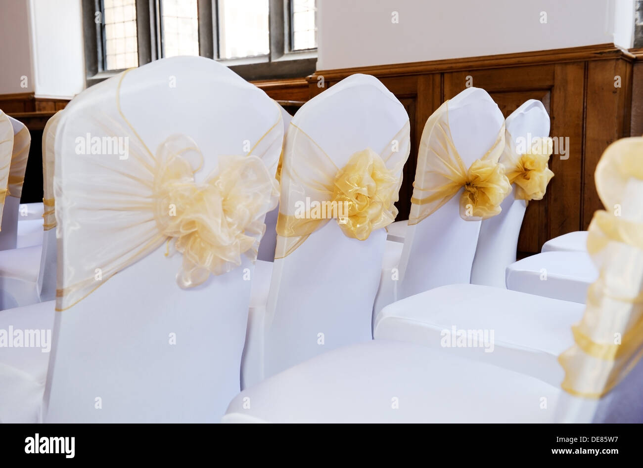Wedding ceremony chairs with white covers and yellow bows Stock Photo