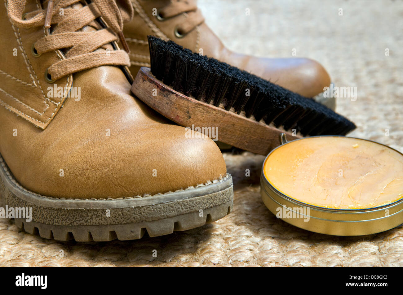 Tan shoe polish with brush and pair of boots waiting to be polished on  woven mat Stock Photo - Alamy