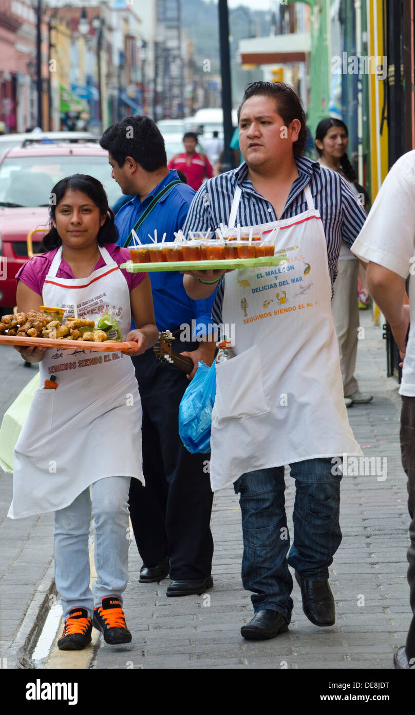 A man and a woman on their way to deliver party food walking  in a busy street in Cholula, Puebla. Stock Photo
