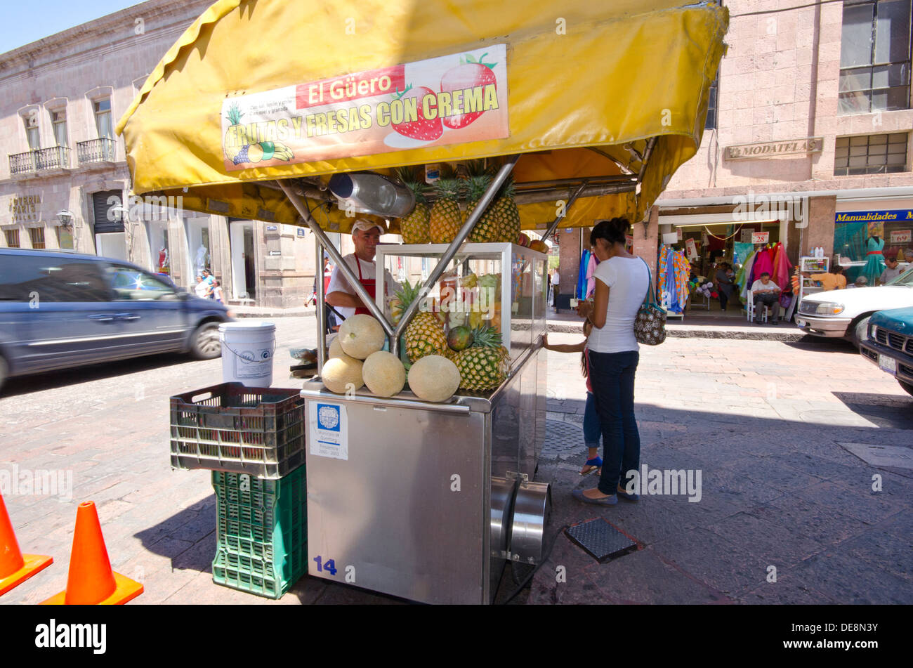Vendor on street corner selling fresh fruit from his mobile stall in