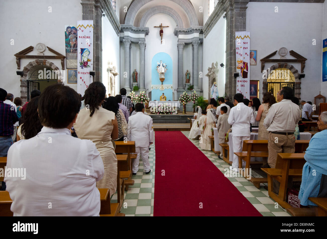Catholic priest conducts a mass for First Communicants in the Santa Maria church in Tequisquiapan in Mexico Stock Photo