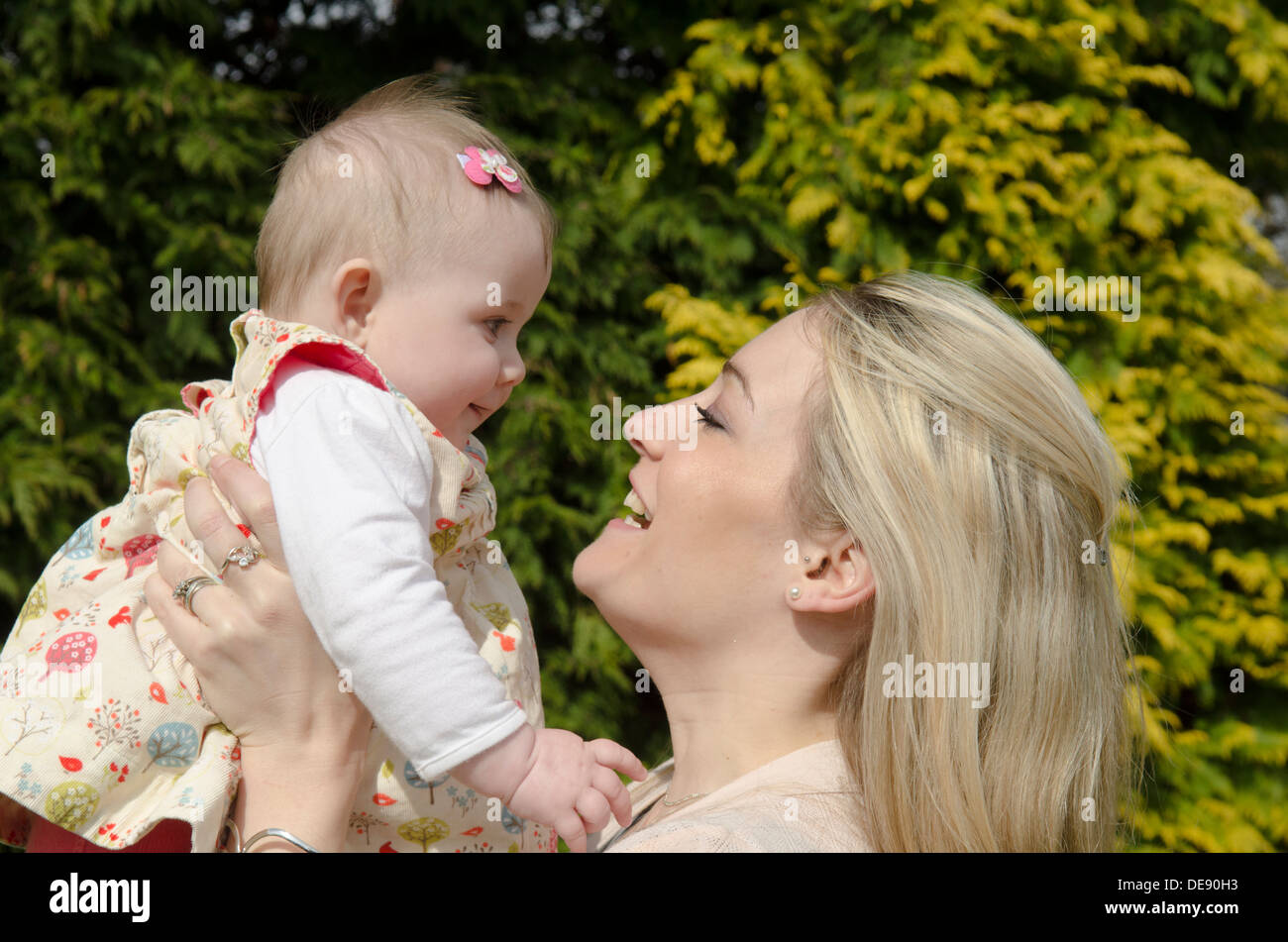 young mother with eight month old baby girl in garden Stock Photo