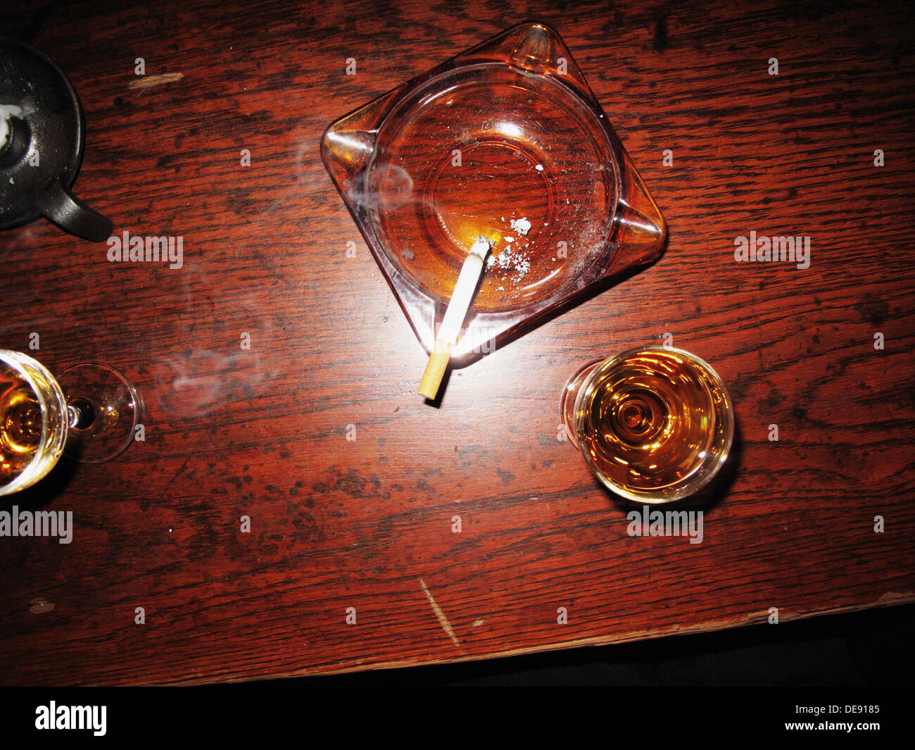 Ashtray With Cigarette and Wine Glasses on Table in Bar, High Angle