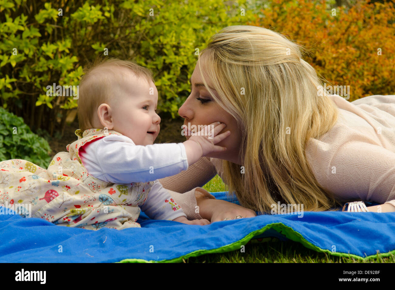 mother playing with eight month old daughter outside in garden Stock Photo