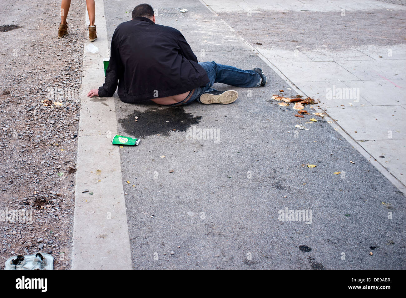 Drunk man sitting on pavement Stock Photo