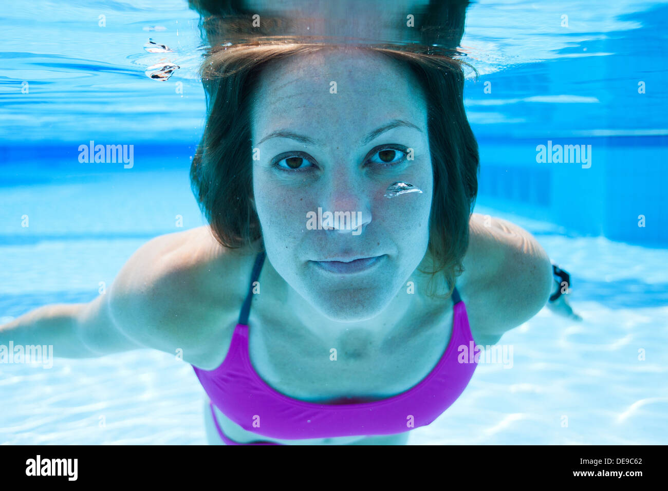 Closeup of female swimmer underwater in swimming pool with eyes open