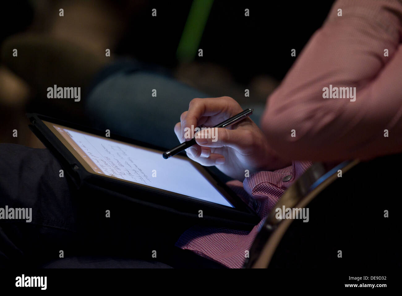 Delegate making notes on an ipad at a conference Stock Photo