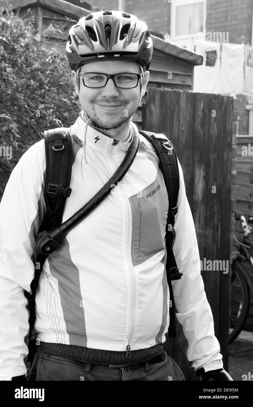 Black and white portrait of a man wearing cycling clothes, helmet and glasses smiling Stock Photo