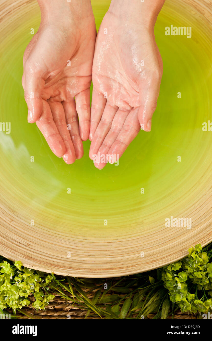 Woman's hands bathing in green liquid at health spa in natural environment Stock Photo