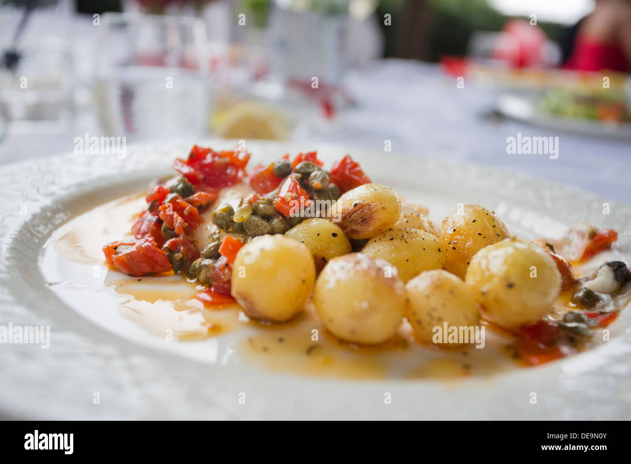seabass with pile of tomatos and capers in italian outside dining area Stock Photo