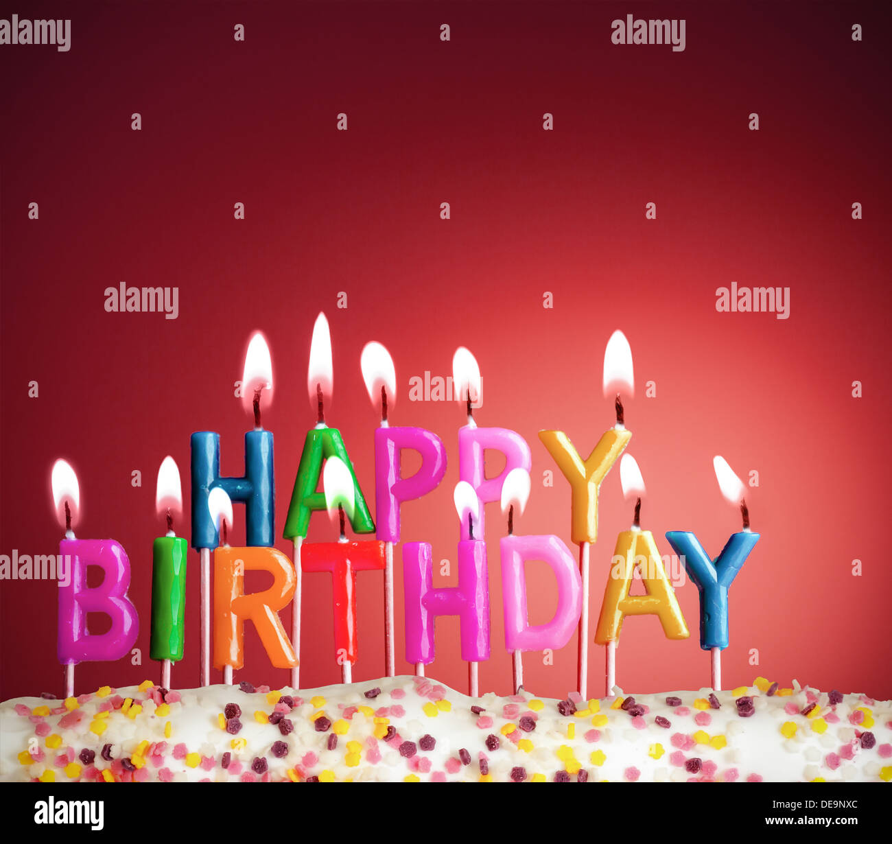 Happy birthday lit candles on red background Stock Photo