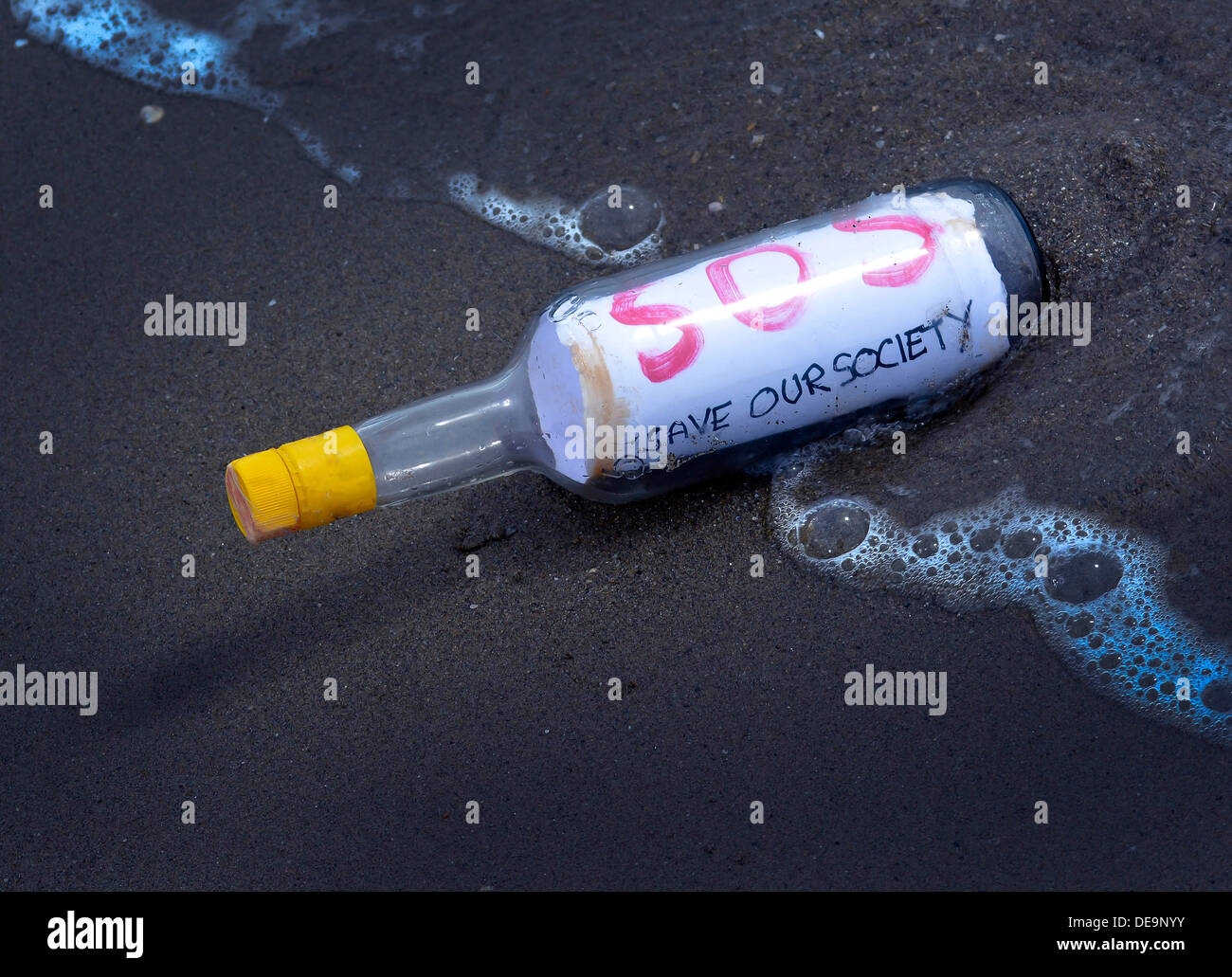 A bottle contains a message - SOS. It has been washed up on the beach Stock Photo