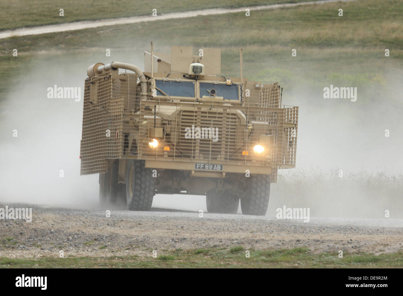 A British Army Mastiff patrol vehicle at speed creates a dust cloud on Salisbury Plain Stock Photo