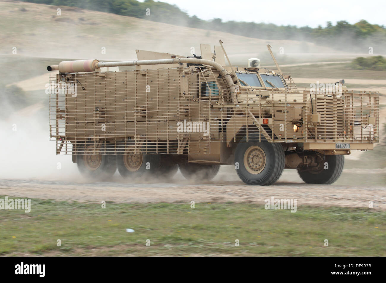 A British Army Mastiff patrol vehicle at speed creates a dust cloud on Salisbury Plain Stock Photo