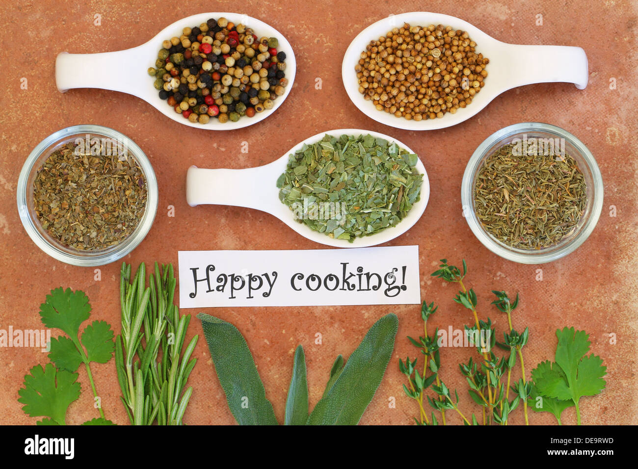 Happy cooking card with selection of herbs and spices on terracotta surface Stock Photo