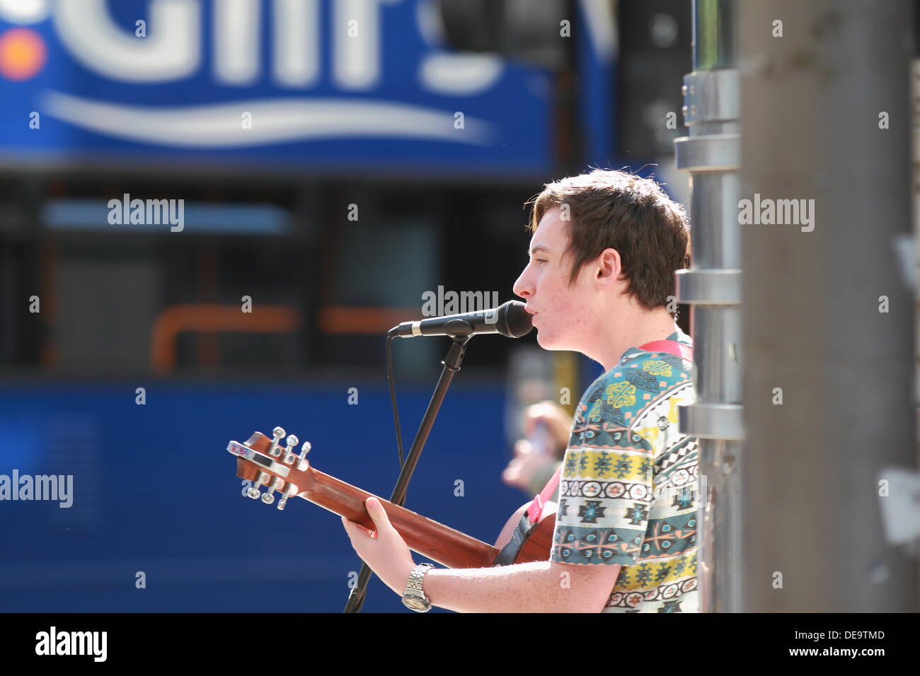 A young man busker sings and plays acoustic guitar to crowds in Glasgow City Centre, Scotland, UK Stock Photo