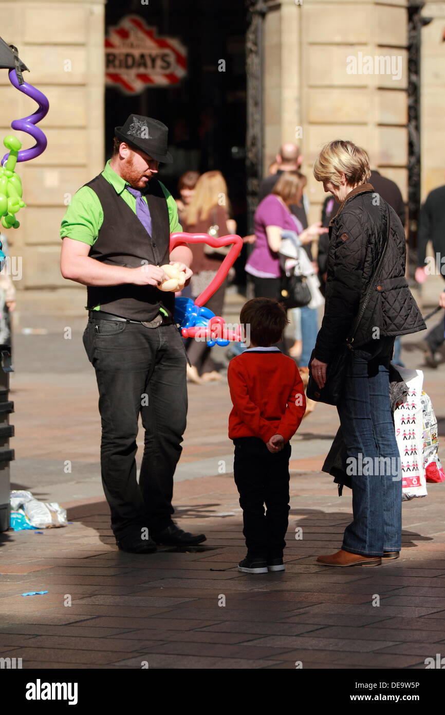 Man creates inflatable animals from balloons for a child, in Buchanan Street, Glasgow, Scotland, UK Stock Photo