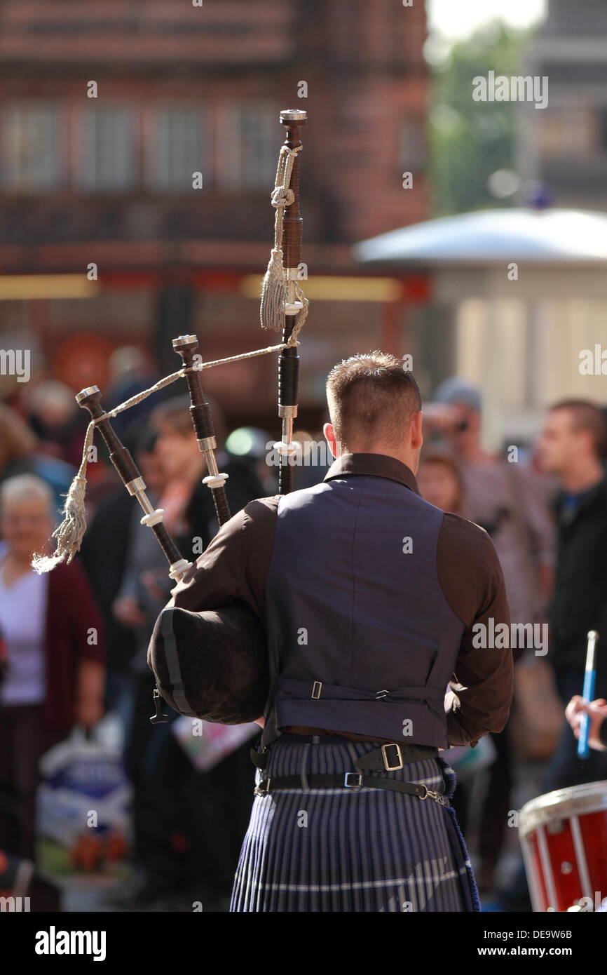 Lone piper plays the bagpipes to a crowd in Buchanan Street, Glasgow, Scotland, UK Stock Photo