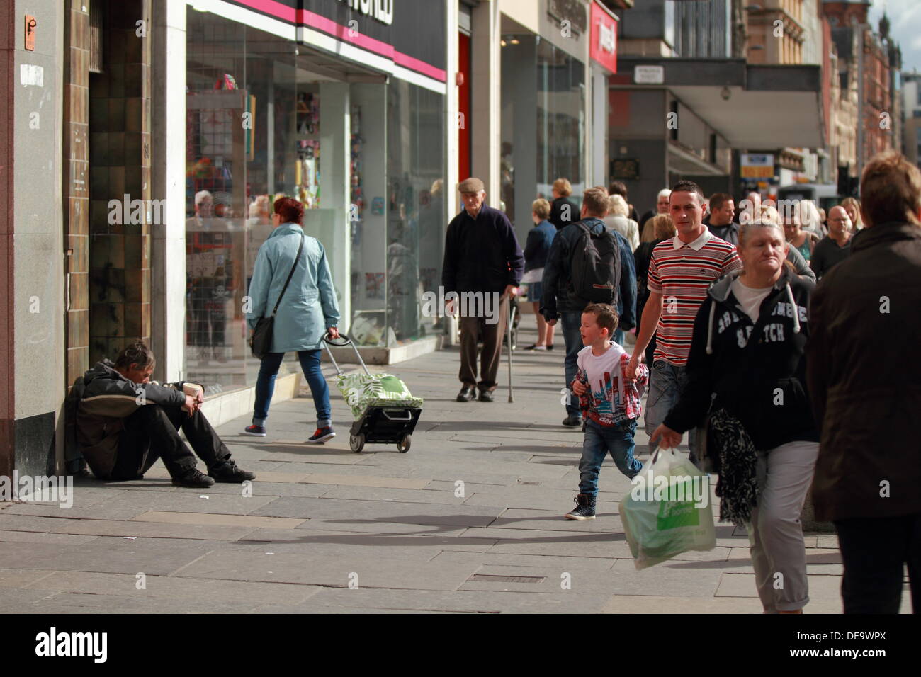 A drunk homeless man begs for money, dirty, poor, poverty, homeless and alone Argyll Street, Glasgow, Scotland, UK Stock Photo