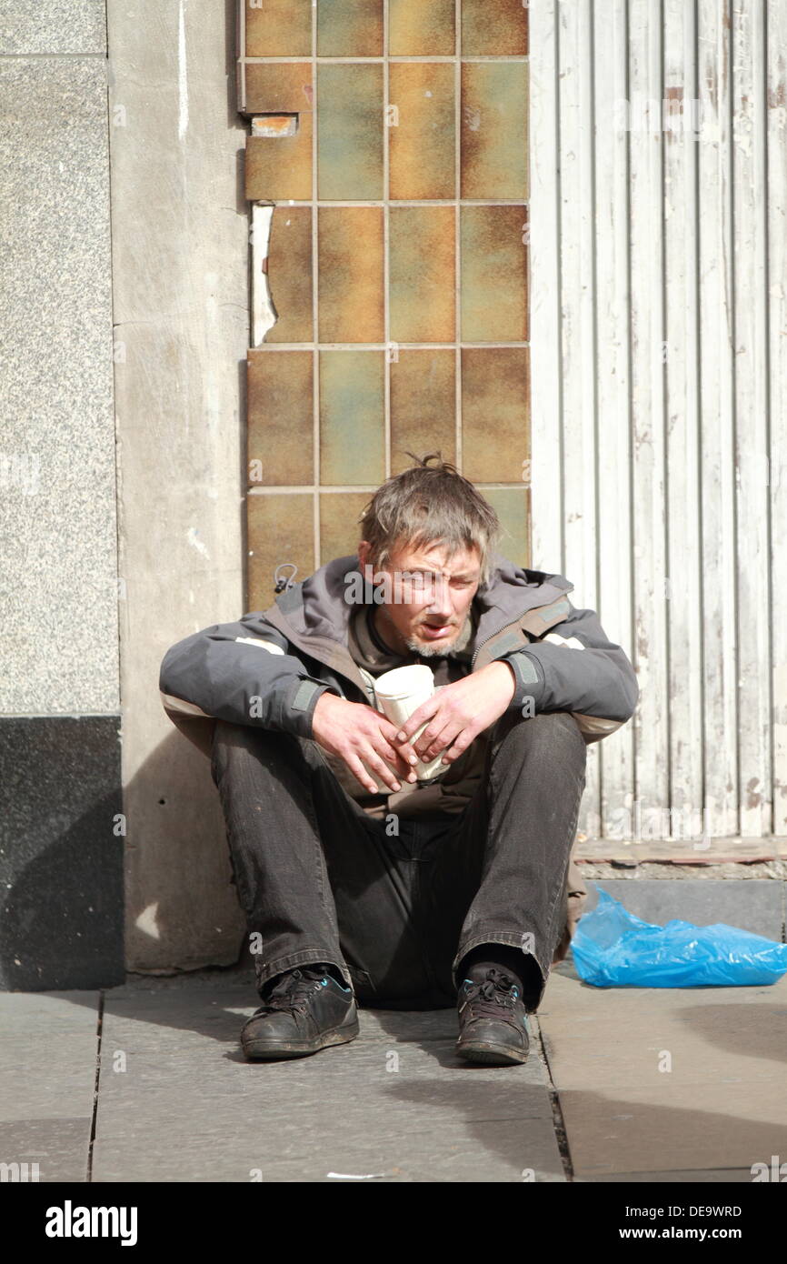 A drunk homeless man begs for money, dirty, poor, poverty, homeless and alone Argyll Street, Glasgow, Scotland, UK Stock Photo