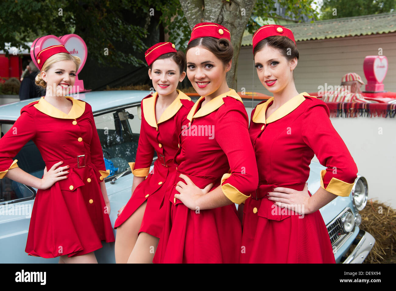 Chichester, West Sussex, UK. 13th Sep, 2013. Goodwood Revival. Goodwood Racing Circuit, West Sussex - Friday 13th September. Glamcabs girls pose for the camera in their red and gold uniforms. © MeonStock/Alamy Live News Stock Photo