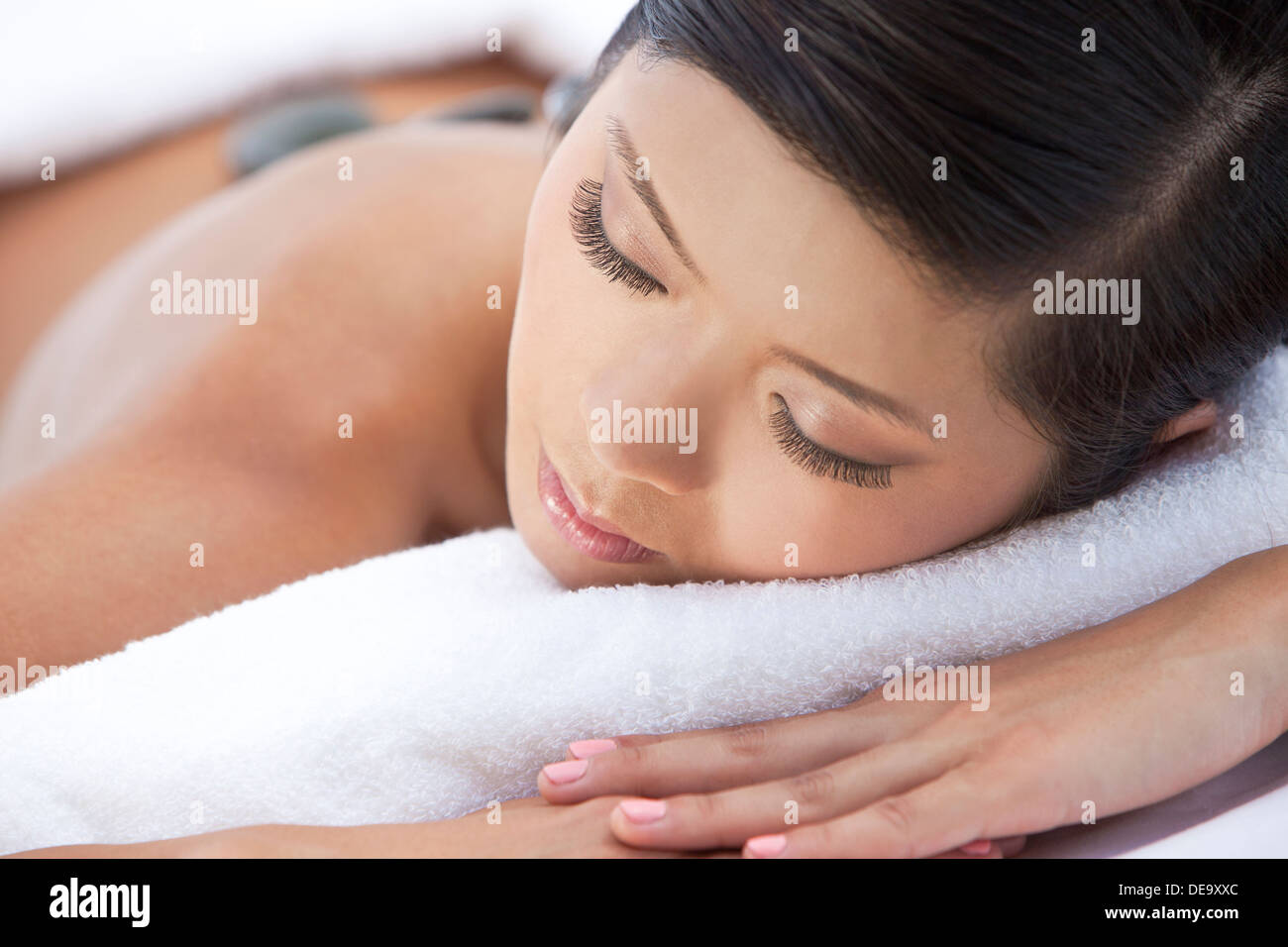 An Asian Chinese woman relaxing at a health spa while having a hot stone treatment or massage Stock Photo