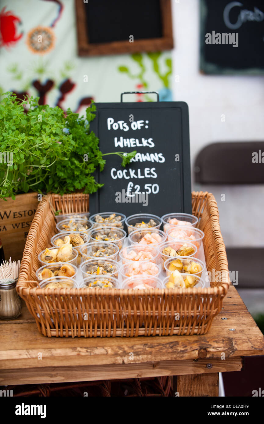 Little pots of fresh and tasty whelks, prawns and cockles on sale in a wicker basket food tent at a summer festival Stock Photo
