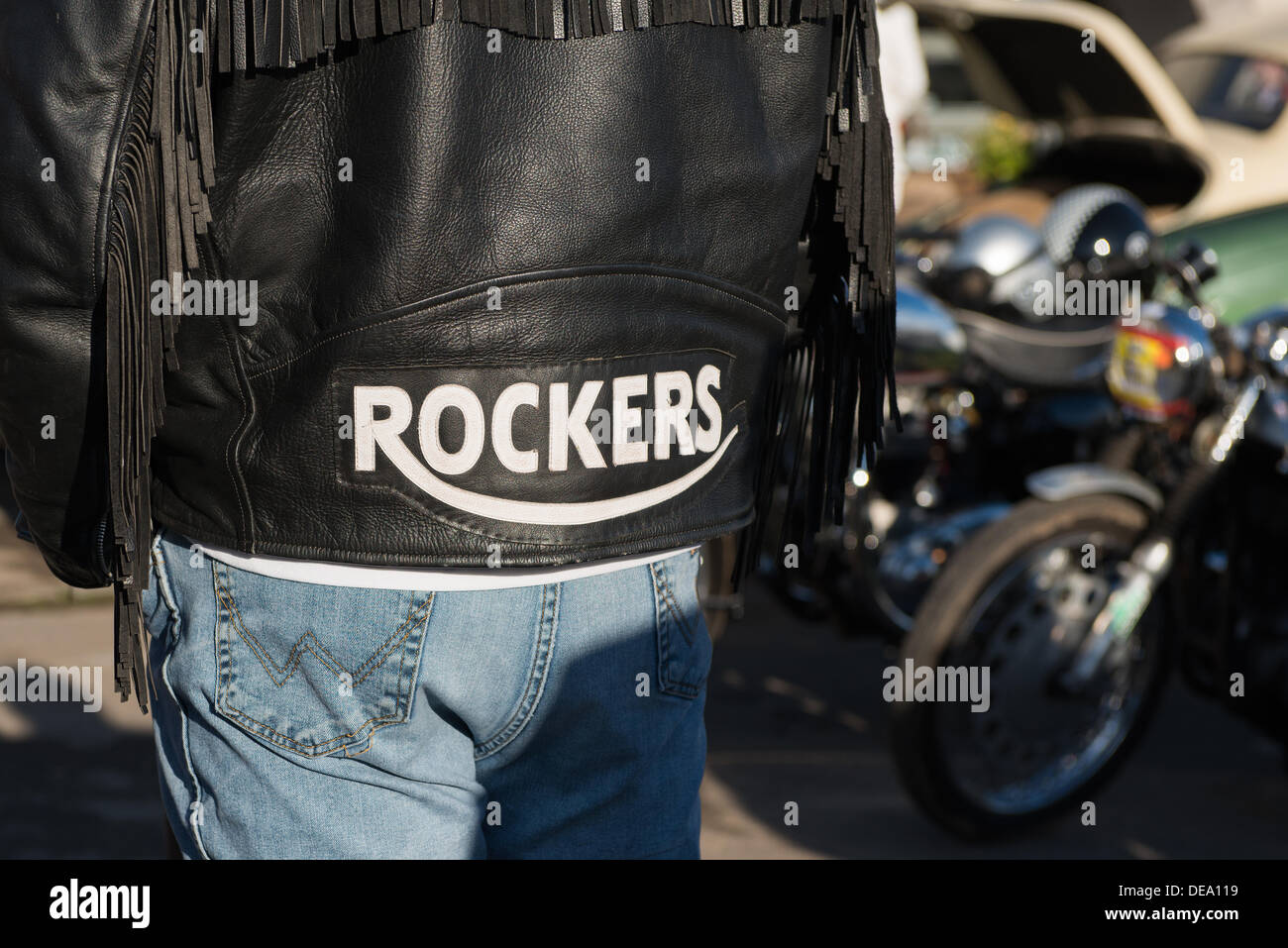 Chichester, West Sussex, UK. 14th Sep, 2013. Goodwood Revival. Goodwood Racing Circuit, West Sussex - Saturday 14th September. A black leather jacket with Rockers emblazoned across the back is worn by a man standing next to some vintage motorbikes. Credit:  MeonStock/Alamy Live News Stock Photo